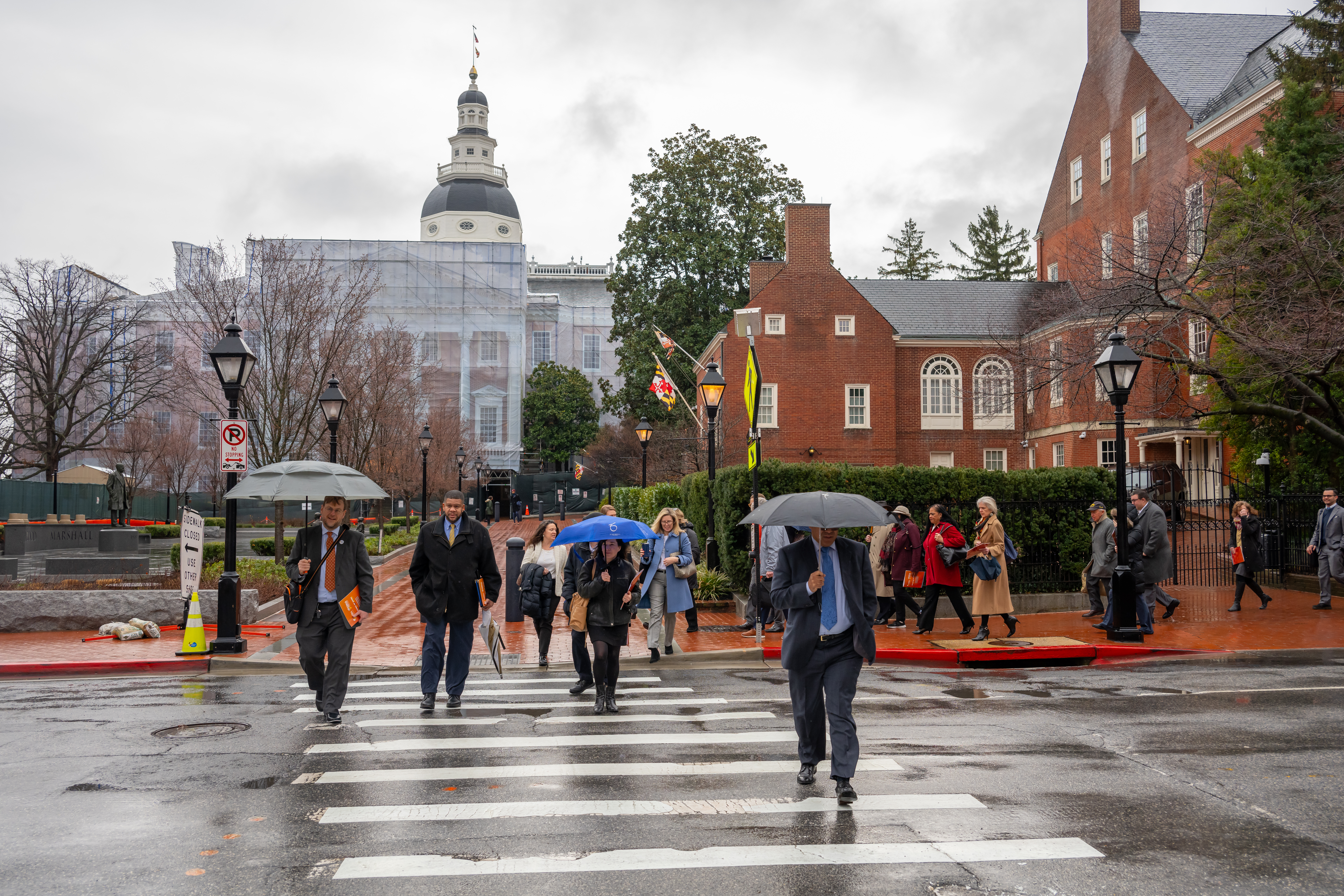 MSBA members walk down the street in front of the Maryland State House in Annapolis on a rainy day.