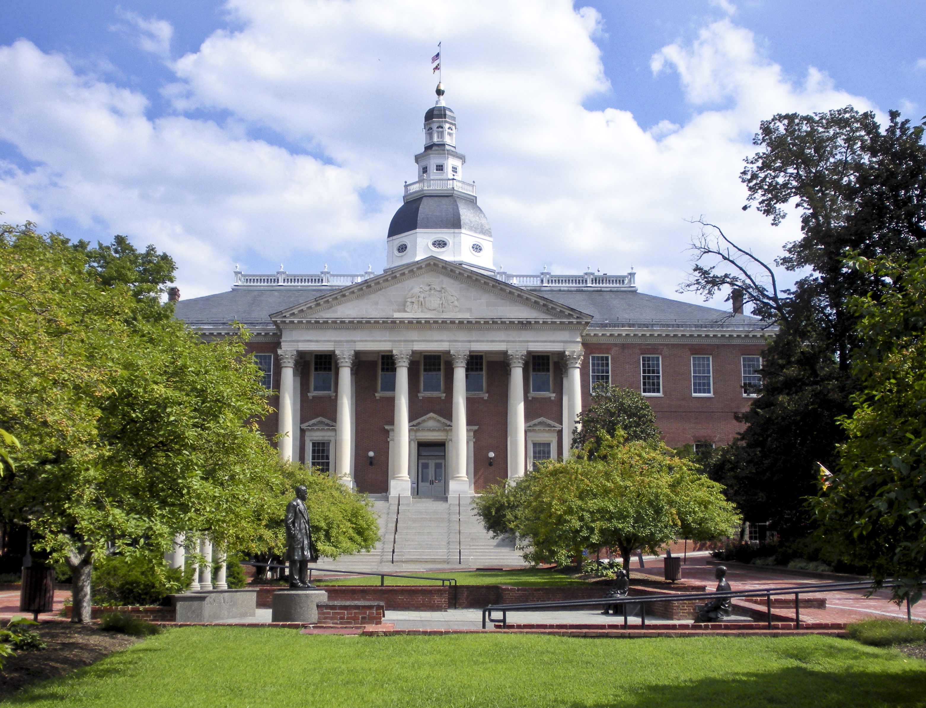 Maryland's State House building, a red brick building with a white dome, on a sunny day with blue skies.